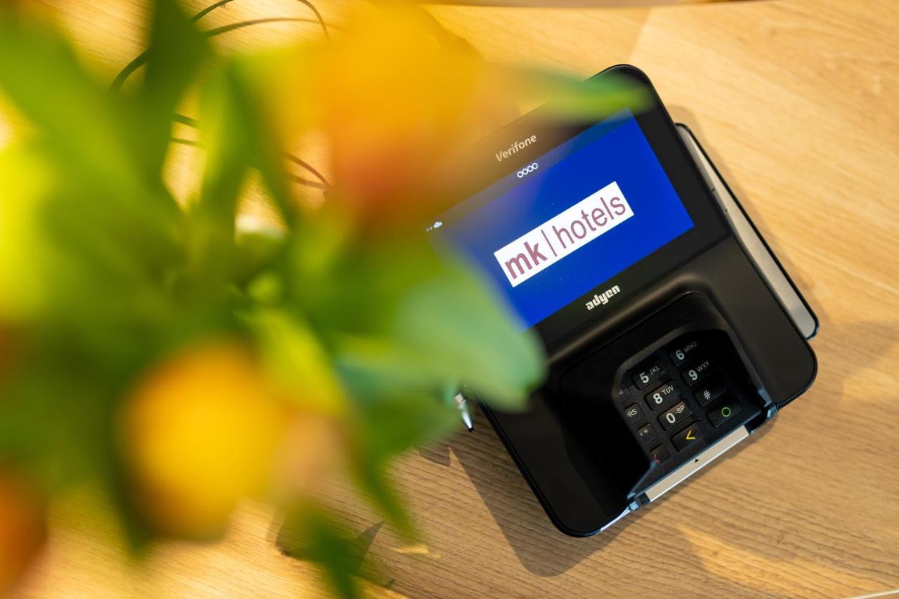 Mk Hotel Tirana Rinas المظهر الخارجي الصورة A mobile phone with the MK1Hotels logo on the screen